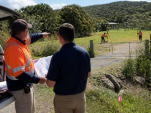 Surveyor reviewing property access and site conditions while a field crew measures a gated parcel in Fort Lauderdale, Florida.